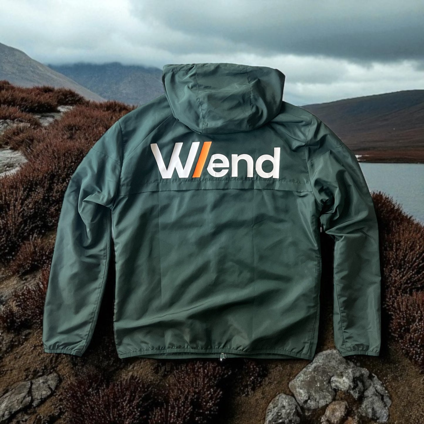 W/end Windbreaker Forest Green Jacket with a logo on a mountainous landscape